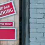 Hiring sign taped to a brick wall beside an apply today notice