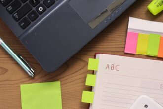 A laptop, an open notebook and a pen on a wooden desk