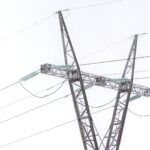 Steel transmission pylon and power lines covered in frost against a white winter sky
