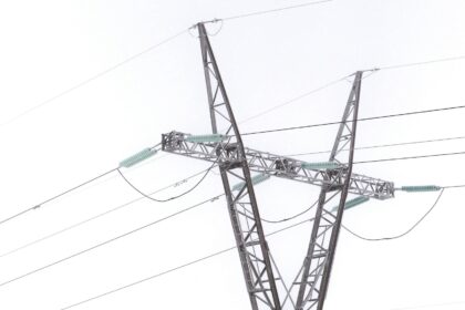Steel transmission pylon and power lines covered in frost against a white winter sky
