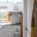 Kitchen with white cabinets covered in plastic sheeting during a renovation