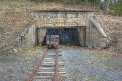 Concrete mine portal with a lettered panel reading Brazeau Collieries Ltd Nordegg No. 2, a chain-link gate, a small ore cart and a rail track running toward the camera