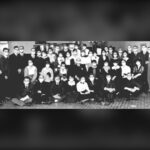 Rows of bank staff in a Calgary branch posed together, wearing white face masks, in a black and white 1918 photograph