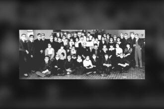 Rows of bank staff in a Calgary branch posed together, wearing white face masks, in a black and white 1918 photograph