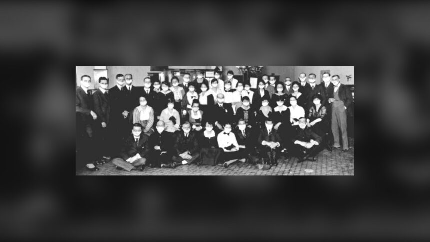Rows of bank staff in a Calgary branch posed together, wearing white face masks, in a black and white 1918 photograph