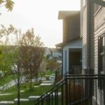 Row of townhouses with front porches on a tree-lined residential street in Calgary