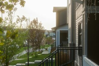 Row of townhouses with front porches on a tree-lined residential street in Calgary