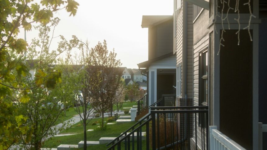 Row of townhouses with front porches on a tree-lined residential street in Calgary