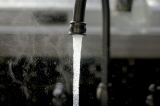 Water running from a dark kitchen tap into a sink