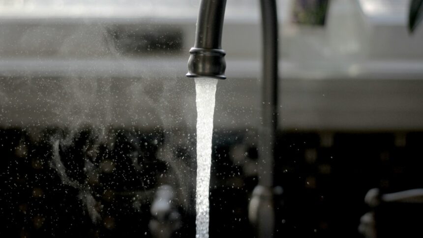 Water running from a dark kitchen tap into a sink