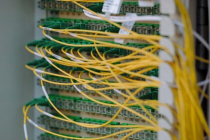Yellow fibre optic patch cables looped across a rack of green connectors