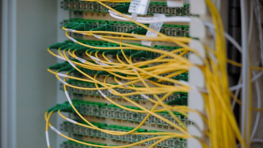 Yellow fibre optic patch cables looped across a rack of green connectors