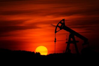 Silhouette of an oil pumpjack against a red sunset