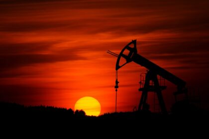Silhouette of an oil pumpjack against a red sunset