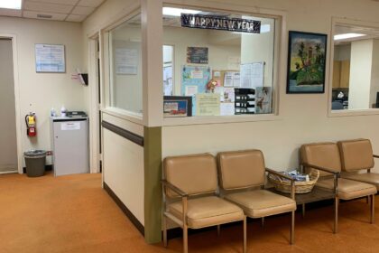 Hospital waiting room with padded chairs beside a reception window