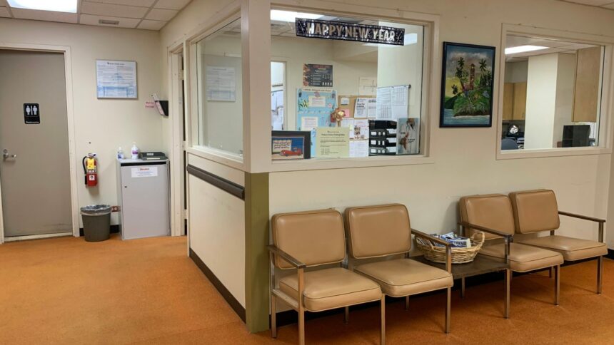 Hospital waiting room with padded chairs beside a reception window