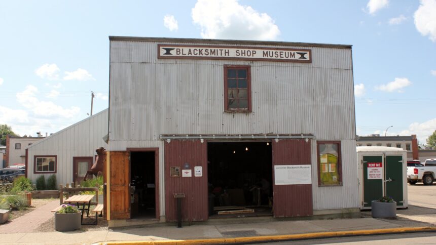 Front of the Lacombe Blacksmith Shop Museum, a corrugated metal building with a Blacksmith Shop Museum sign above open sliding doors