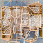 Overhead view of a new house under construction, with wood wall framing and roof trusses laid out across the subfloor