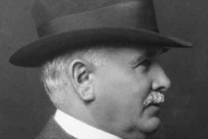Black and white portrait of Patrick Burns in a hat and suit, shown in profile, photographed in 1927