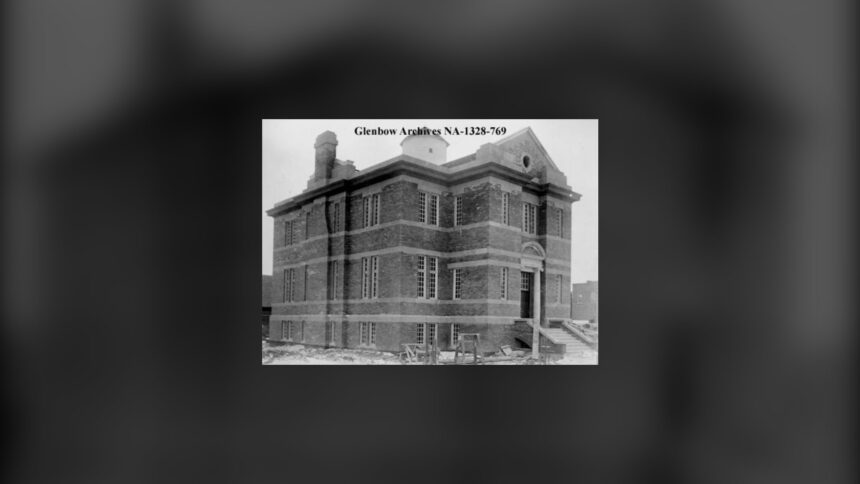 A two-storey brick library building with a tall entrance, standing alone on an open lot, in a black and white 1913 photograph