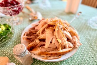 Platter of carved roast turkey on a Thanksgiving table with cranberry sauce and side dishes